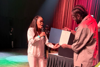 Aidonia being presented with proclamation by a representative from the City of Boston